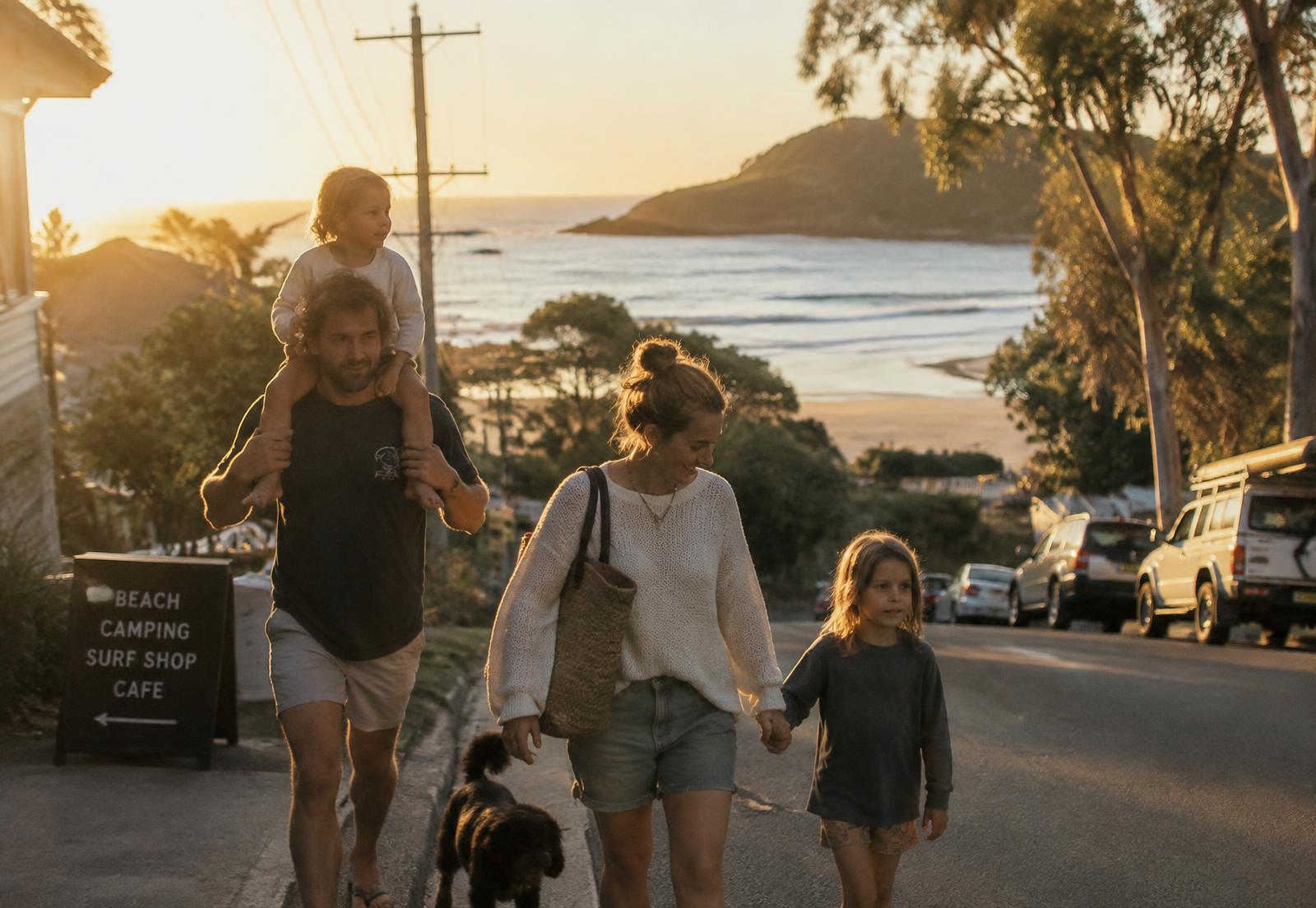 A family walking down a coastal street in a regional New South Wales town at sunset